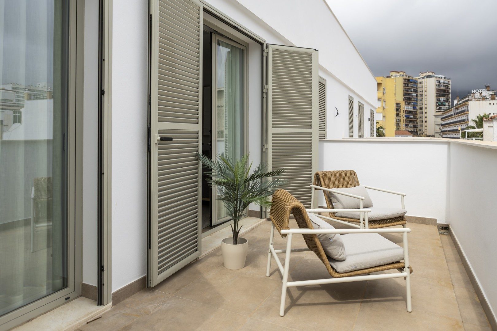 Terraza privada de Cauce4 con dos sillones de mimbre y vistas a la ciudad